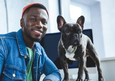 Young man with French bulldog by computer screen
